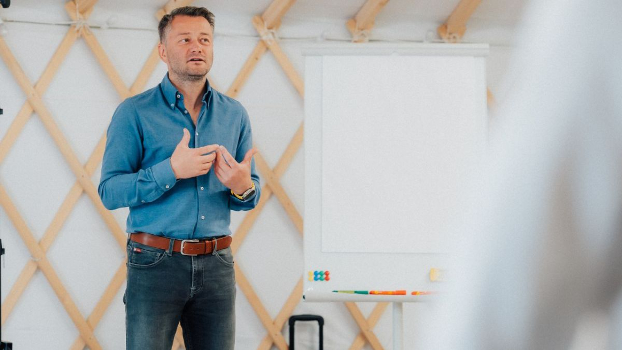 Jarosław Kuźniar - trener public speaking podczas prezentacji w nowoczesnej sali szkoleniowej