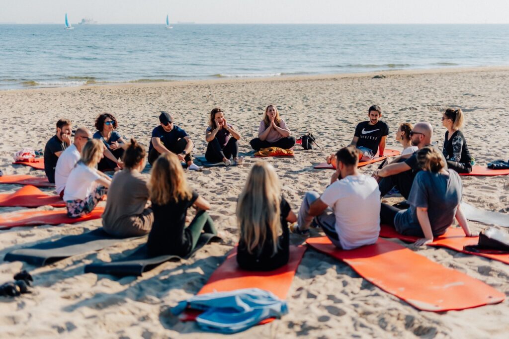 Outdoor training public speaking na plaży - uczestnicy warsztatów siedzą w kręgu podczas sesji grupowej